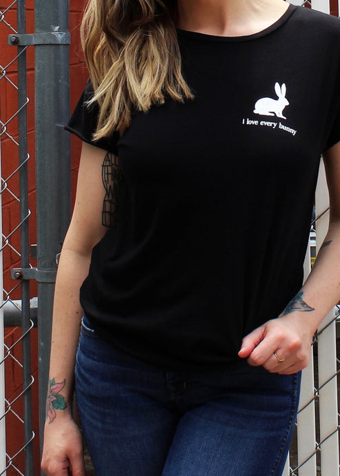 Female modeling a black relaxed fit graphic tee with white print on the left chest that reads I Love Every Bunny under a bunny image.